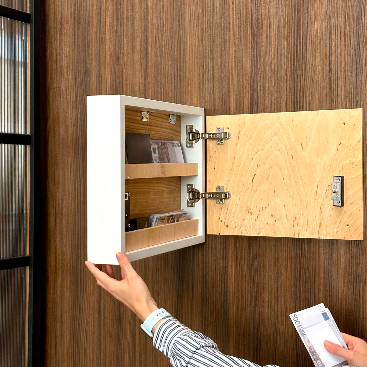 Close-up of concealed storage compartment behind fishing wall art with shelves for cash and documents