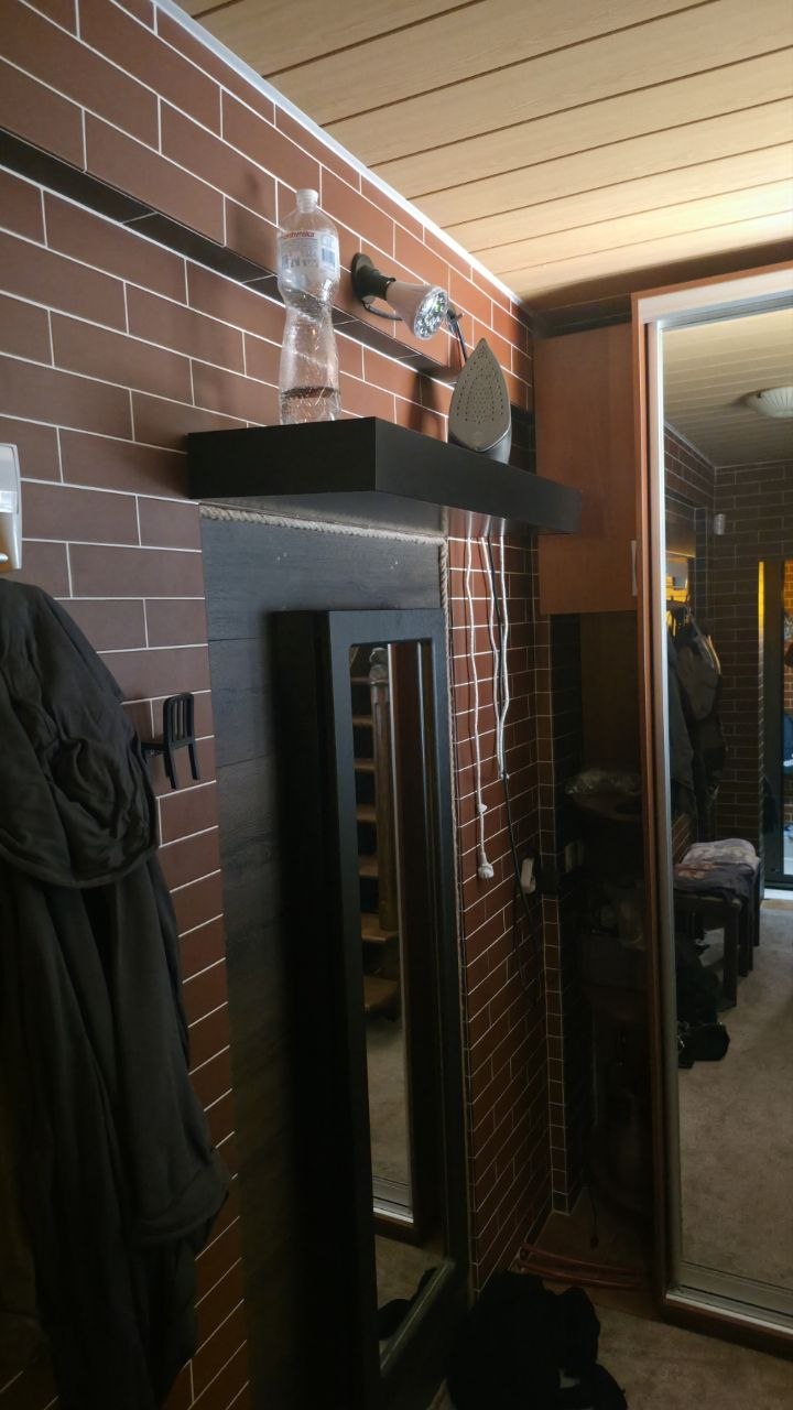 Black Hiddo floating wall shelf above a mirror in a utility room