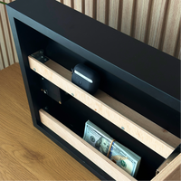 Modern Wave Wall Art with Concealed Storage. A black and wood safe or storage cabinet shown open, with a stack of cash in the lower compartment and a small round black device resting on a wooden shelf.