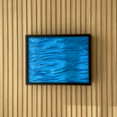 Modern Wave Wall Art with Concealed Storage. A framed square wall art piece featuring a textured blue water-ripple design, mounted on a light wood slatted wall.