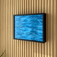 Modern Wave Wall Art with Concealed Storage. A framed wall art piece featuring a textured blue abstract water-like pattern, mounted on a light wood slatted wall.