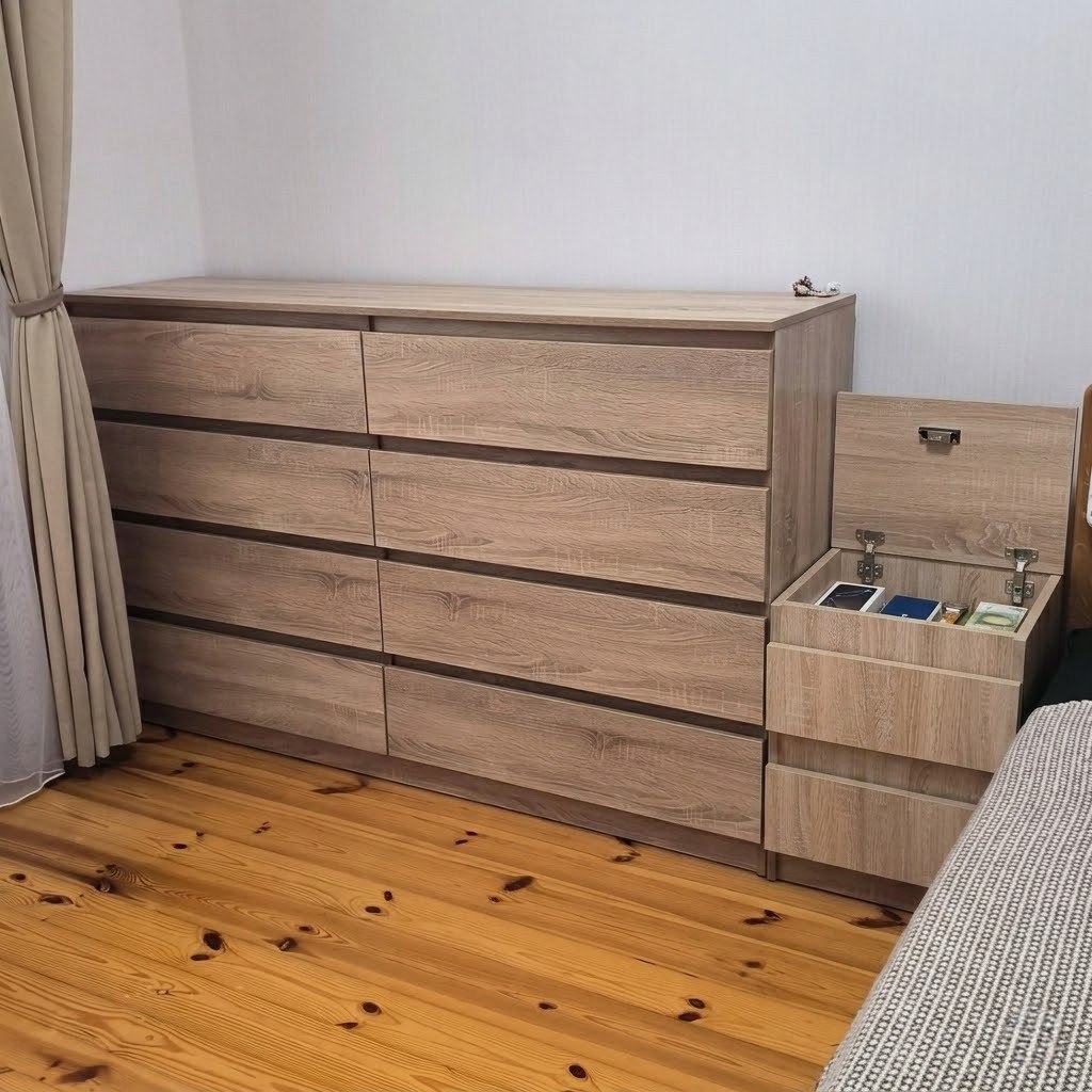 Light oak Hiddo nightstand with its hidden top compartment open beside a matching dresser