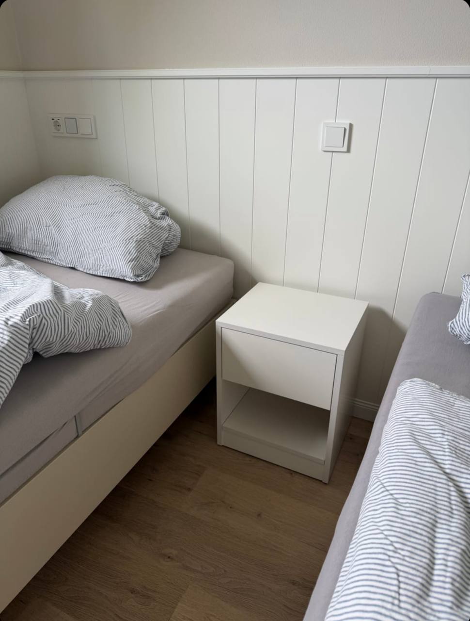 White Hiddo nightstand B28 with a drawer and open lower shelf between two beds