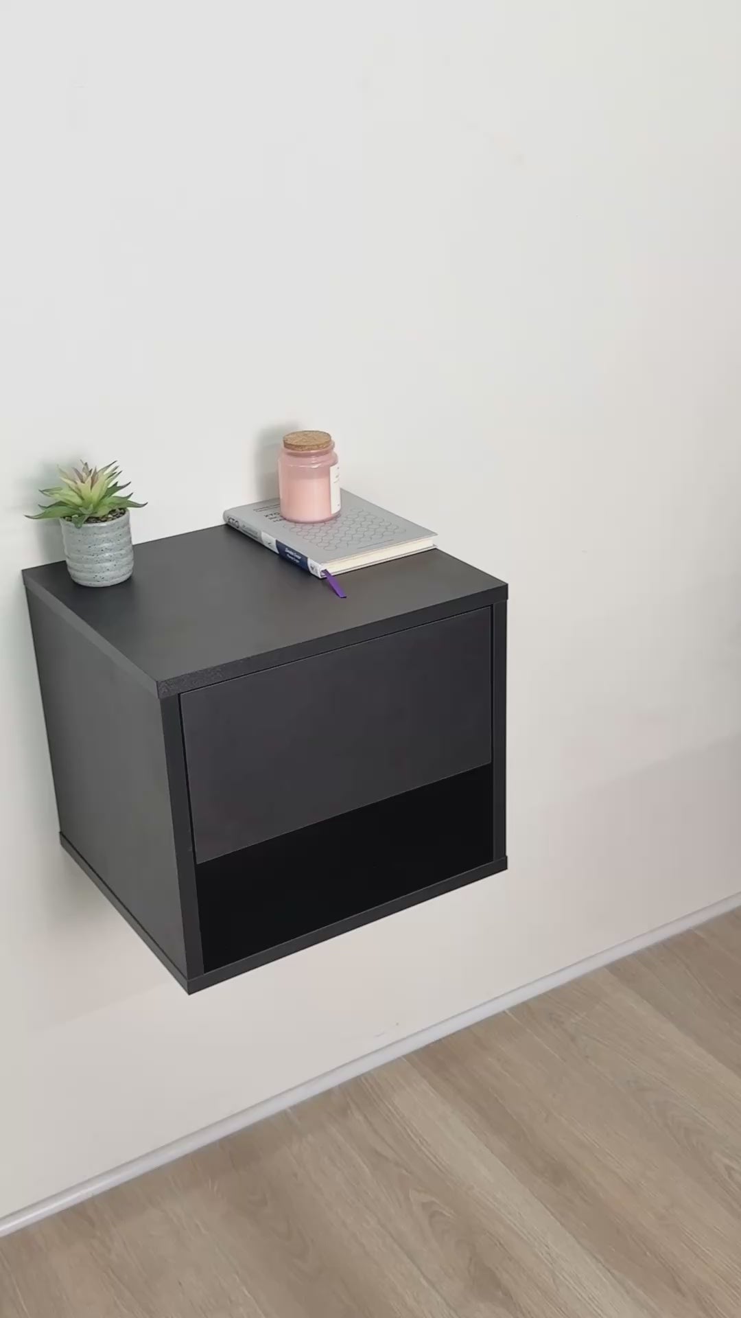 The video shows a black B40 wall-mounted nightstand with main drawer and concealed side drawer open beside a bed